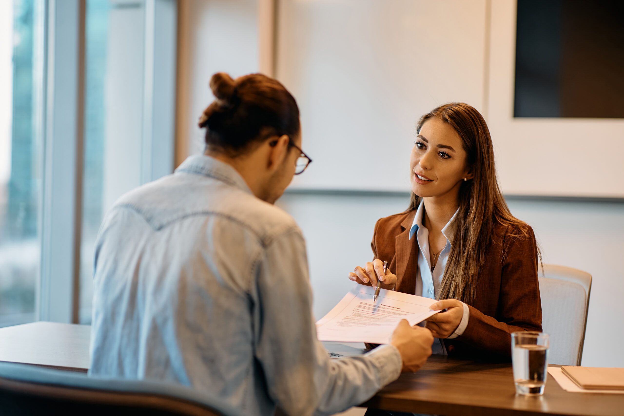 Young bank manager going through agreement with her client during meeting in office.